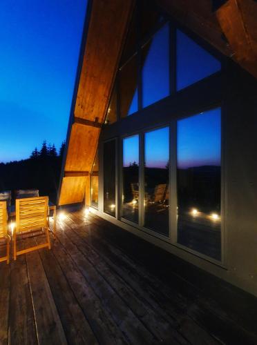 a wooden deck with a bench and windows at night at Vrleti Tare in Bajina Bašta