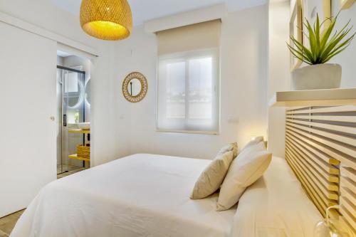 a white bedroom with a large bed and a window at Brasil 104 in Torremolinos