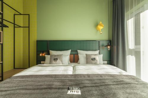 a bedroom with a large bed with white pillows at Holiday Inn - the niu, Dwarf Berlin Schöneberg by IHG in Berlin