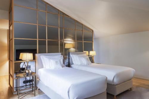 two beds in a hotel room with white sheets at Casa da Companhia Hotel & Spa, Vignette Collection by IHG in Porto