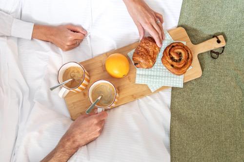 a man laying in bed with a tray of food at Appart Hotel Neostelia in Annecy