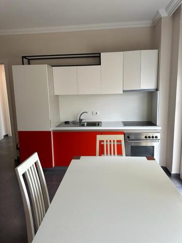 a kitchen with red and white cabinets and a table and chairs at Deluxe Apartments Shengjin in Shëngjin