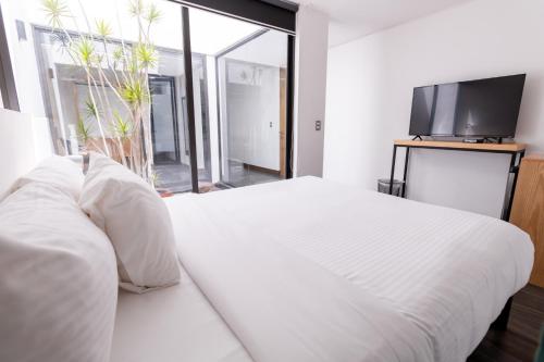 a bedroom with a white bed and a large window at Urban Puebla by Grupo Amber in Puebla