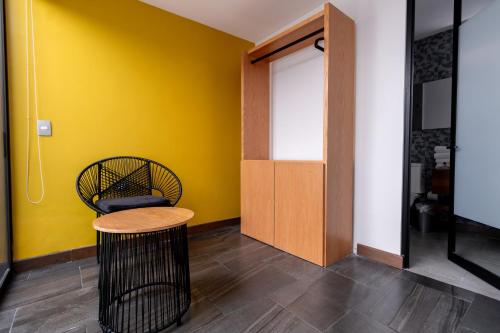 a room with a yellow wall and a stool and a door at Urban Puebla by Grupo Amber in Puebla
