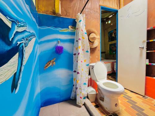 a bathroom with a toilet and a shower curtain at Los Gulungos Hostel in Jardin