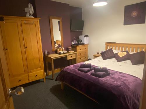 a bedroom with a bed with a purple comforter at Butterfly House in Blackwood