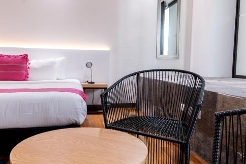a room with a bed and a chair and a table at Urban Puebla by Grupo Amber in Puebla