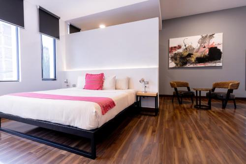 a bedroom with a bed and a table and chairs at Urban Puebla by Grupo Amber in Puebla