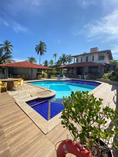 una piscina con terrazza in legno accanto a una casa di Casa de Praia Olivença a Ilhéus