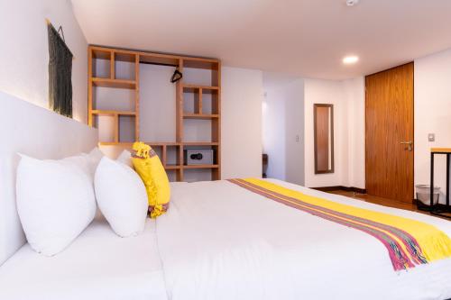 a bedroom with a white bed with white pillows at Urban Puebla by Grupo Amber in Puebla