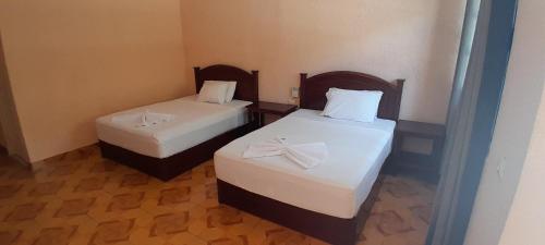 two beds in a small room with white sheets at Hotel yaakunah in Escárcega