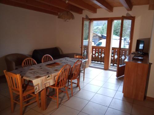 une salle à manger avec une table et des chaises et un balcon dans l'établissement Location Les dents blanches, à Morillon