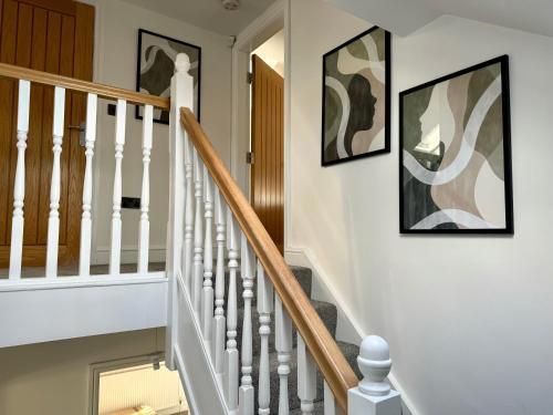 a white staircase with two pictures on the wall at 3 bed flat in Holmes Chapel Harry Styles village in Holmes Chapel