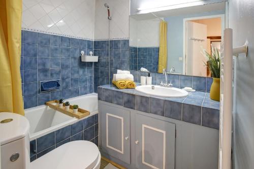 La salle de bains est pourvue de carrelage bleu, de toilettes et d'un lavabo. dans l'établissement Le Soleil Bleu, à Nîmes