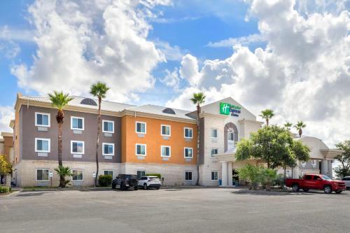 a hotel with cars parked in a parking lot at Holiday Inn Express Hotel and Suites Alice by IHG in Alice