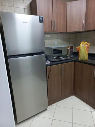 a stainless steel refrigerator in a kitchen with wooden cabinets at عجمان تارو 7 in Ajman 