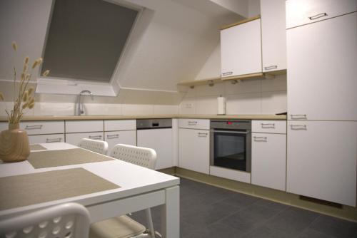 a kitchen with white cabinets and a table and chairs at Smart 1 in Tuttlingen