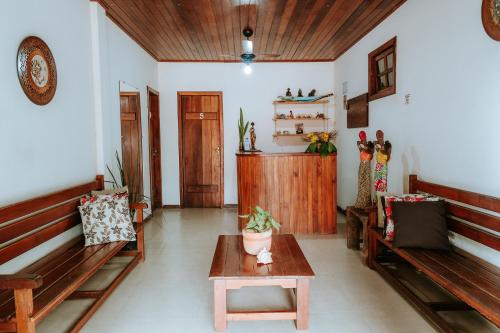 a living room with benches and a table and a door at Pousada Ponta da Baleia in Barra Grande