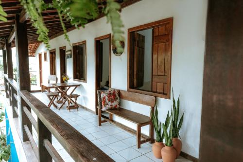 a porch of a house with a bench and a table at Pousada Ponta da Baleia in Barra Grande