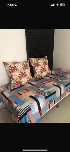 a bed with a colorful comforter and two pillows at Eco Paradise Cumbuco 128 in Cumbuco