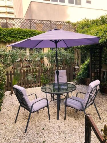 une table avec deux chaises et un parapluie violet dans l'établissement Centre-ville de Cannes 100 m mer, à Cannes
