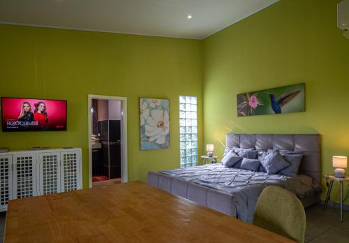 een slaapkamer met groene muren met een bed en een flatscreen-tv bij Finca Colibri in Boca Chica