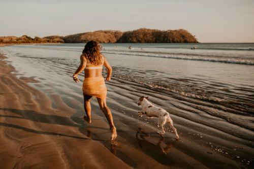 a woman running on the beach with a dog at Villa #35 - Blue Venao, Playa Venao in Playa Venao