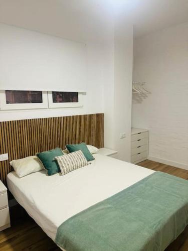 Un dormitorio con una gran cama blanca con almohadas verdes. en Gran apartamento a pie de calle, en Valencia