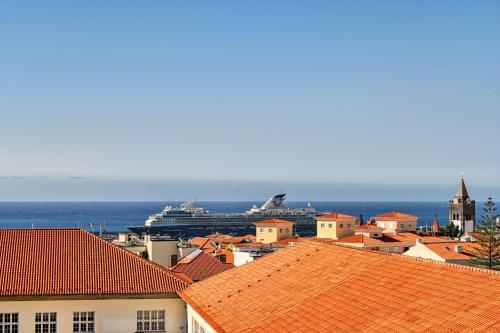 a cruise ship in the ocean next to a city at Maranta House, a Home in Madeira in Funchal