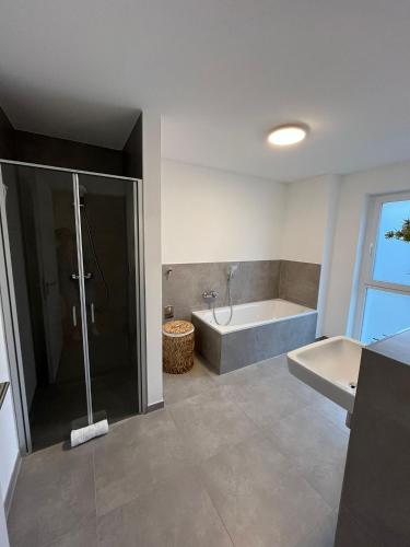 a bathroom with a shower and a tub and a sink at REMA Homes - 180x200 Bett Küche Bad 50'' TV Tiefgarage in Offenburg