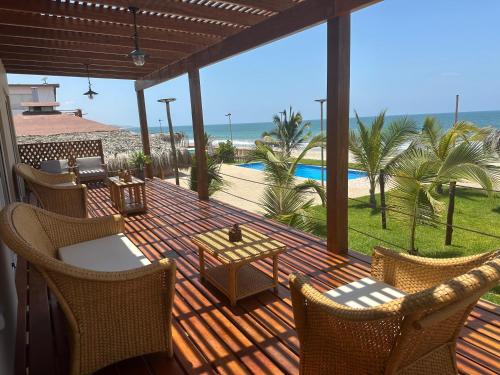 a deck with chairs and a table and a view of the ocean at Hotel Gran Azul Bungalows in Canoas De Punta Sal