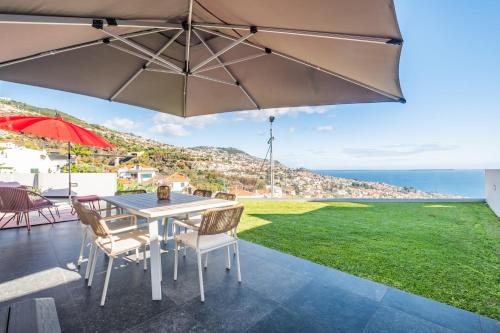 a patio with a table and chairs and an umbrella at Bayview Villa Retreat in Funchal