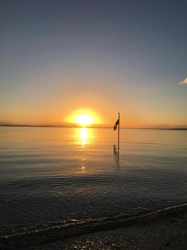 a flag in the water with the sunset in the background at Sea-batical Retreat in Auckland