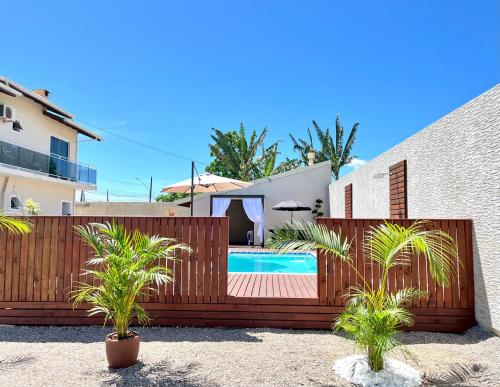 a wooden fence with plants in front of a swimming pool at Acomodação Cambirela in Palhoça