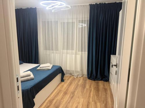 a small room with a bed and blue curtains at Apartament Sophia in Craiova
