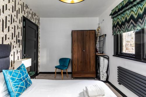 a bedroom with a bed and a blue chair at Locksbrook Lodge - Hot Tub - Spacious Outdoor Space in Bath