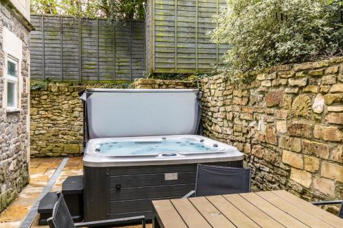 a jacuzzi tub in a backyard with a stone wall at Locksbrook Lodge - Hot Tub - Spacious Outdoor Space in Bath
