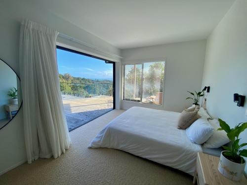 a bedroom with a large bed and a large window at Nestled in Nature, 2 Bedroom Treetop Home in Raglan