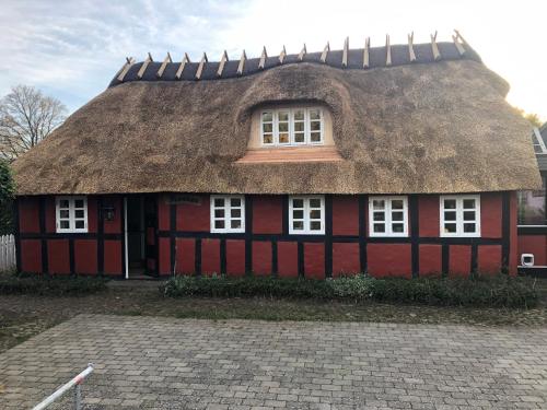 a red and black house with a thatched roof at Hyggeligt gammelt hus i Ry in Ry