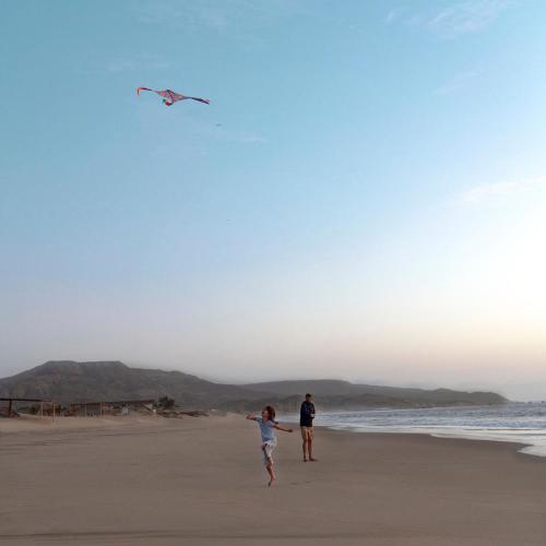 two people flying a kite on the beach at Norte Suites Boutique in Los Órganos