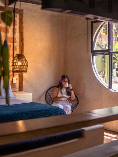 a woman sitting in a chair drinking a cup of coffee at Hotel Casa de Hadas in Minca