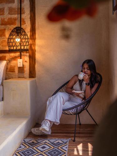 a woman sitting in a chair drinking a cup of coffee at Hotel Casa de Hadas in Minca
