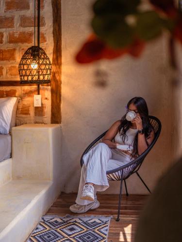 a woman sitting in a chair drinking a cup of coffee at Hotel Casa de Hadas in Minca