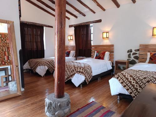 オリャンタイタンボにあるTika bungalows hotelのベッドが3つとポールが1本ある部屋