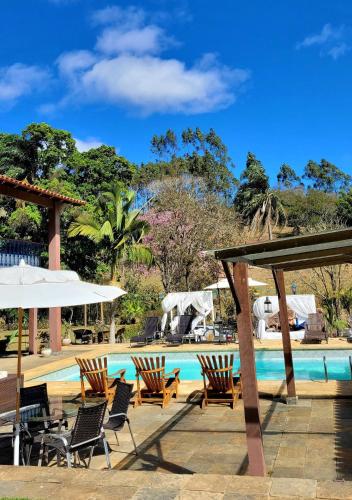 a pool at a resort with chairs and umbrellas at Pousada Solar Azul in Miguel Pereira