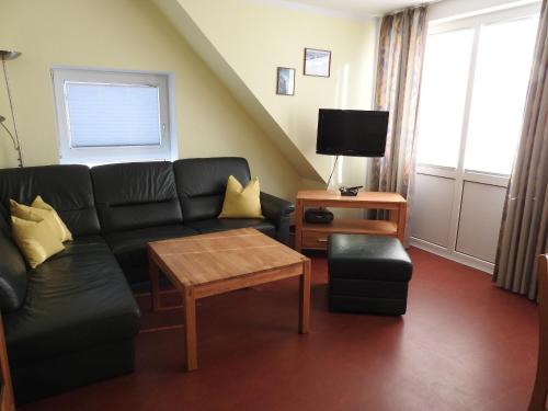 ein Wohnzimmer mit einer schwarzen Couch und einem Tisch in der Unterkunft Ferienwohnung Saalfeld in Schillig