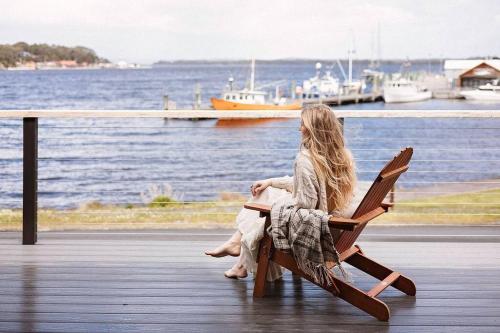 a woman sitting on a bench looking at the water at The Seafarer in Strahan