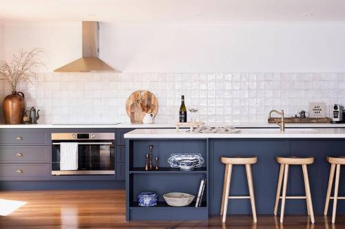 a kitchen with blue cabinets and a counter with stools at The Seafarer in Strahan