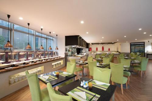 a restaurant with green chairs and tables and a counter at Holiday Inn Shanghai Vista by IHG - Easy access to travel spot city walk in Shanghai