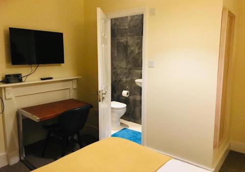a bedroom with a bathroom with a toilet and a television at Vauxhall Stay in London